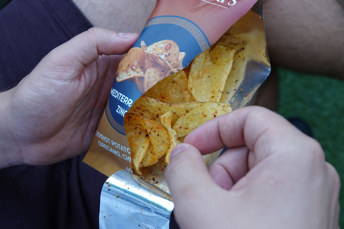 Close-up of fingers reaching into an open bag of Mediterranean Zing